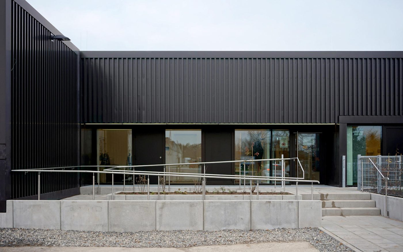Tagesförderstätte Lorsch mit dunkler Metallfassade, Rampe und großen Fenstern