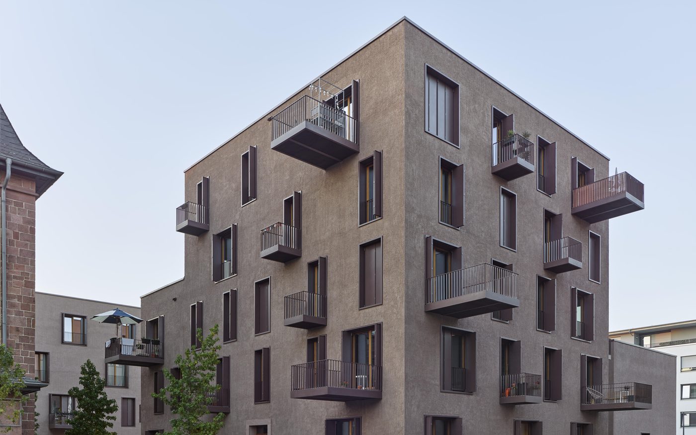 Wohngebäude mit rotbrauner Putzfassade und auskragenden Balkonen auf dem Turley-Areal