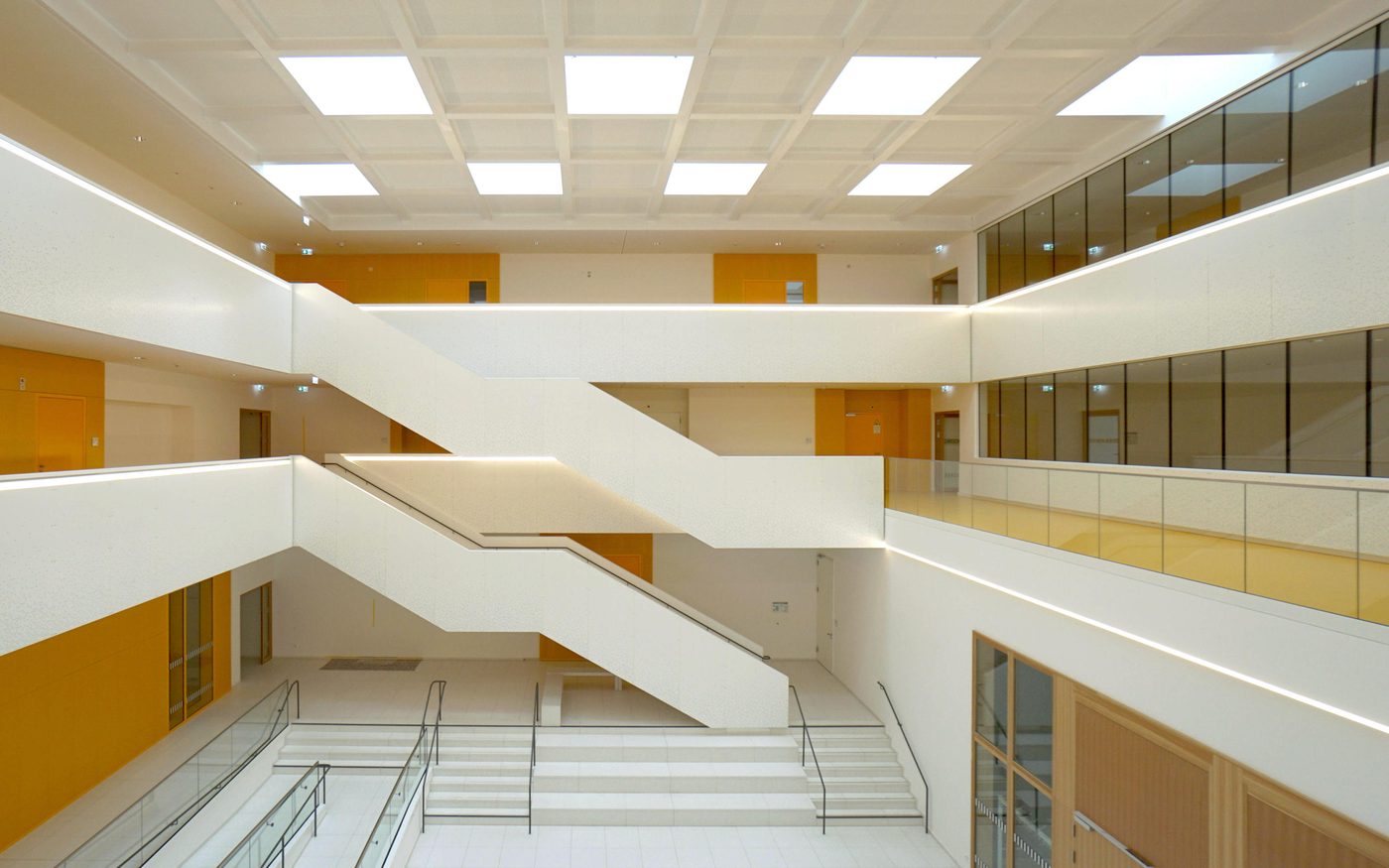 Zentrale Halle mit Treppen und gelben Akzenten
