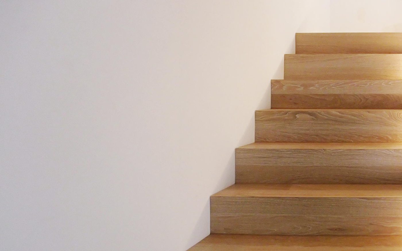 Holztreppe vor heller Wand im Wohnhaus S